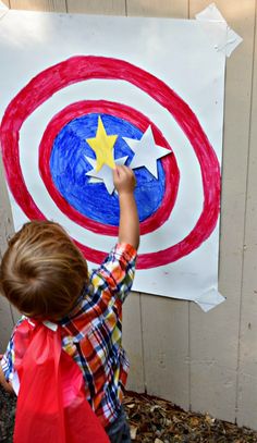 a young boy is painting a red, white and blue shield with yellow stars on it