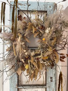 an old door is decorated with dried flowers and leaves for a fall wreath display on the front door