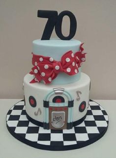 a white cake with red bows and the number 70 on top is sitting on a checkerboard plate