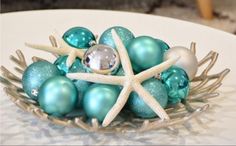 a bowl filled with blue and white ornaments on top of a table next to a starfish