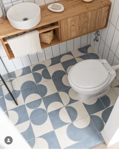 a white toilet sitting in a bathroom next to a wooden counter top and sink under a mirror