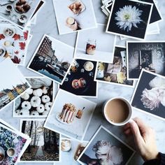 a person holding a coffee cup in front of many pictures on the table with flowers