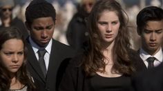 a group of young people standing next to each other in front of a man wearing a suit and tie