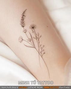 a small tattoo on the leg of a woman's thigh, with flowers growing out of it