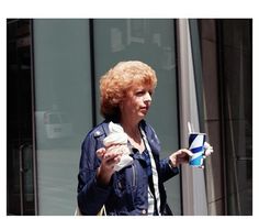 a woman is walking down the street with an ice cream cone in her hand