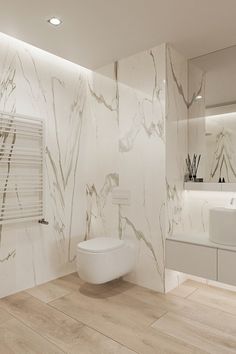 a bathroom with white marble walls and flooring, along with a toilet in the middle