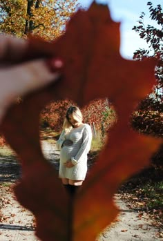 a pregnant woman standing in the middle of a leaf