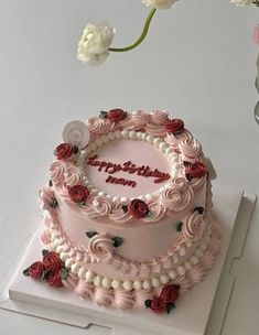 a pink birthday cake with roses on it