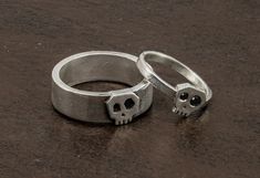 "Set of Handmade Skull rings in Sterling Silver.  These rings have a simple but original and elegant design.  The Little ring skull for her  is shiny, flat and smooth and it has 2 beautiful  black zirconias in the eyes.  The ring for him stands out for the contrast between the small skull and the width of the band that has a very industrial look. Both together are the perfect match. If you are looking for a different engagement rings this set will be the best rings you'll find! In order to make Sterling Silver Skull Ring For Wedding, Rings Alt, Alt Rings, Different Engagement Rings, Sugar Skull Ring, Gothic Wedding Rings, Skull Engagement Ring, Gothic Engagement Ring, Witch Rings