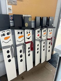 some snowmen are standing next to each other in front of a wall with pictures on them