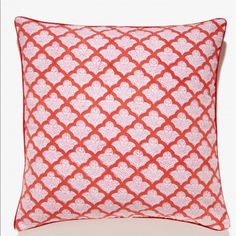 a red and white pillow with an intricate design on the front, sitting on a white surface