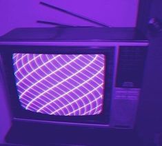 an old fashioned television sitting in front of a purple wall