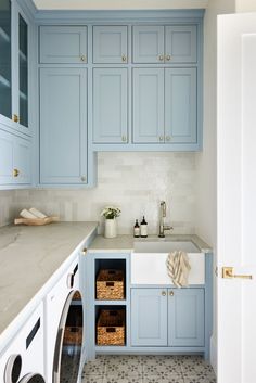 a washer and dryer in a blue kitchen with white counter tops on the counters