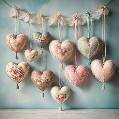 a bunch of heart shaped ornaments hanging from a line on a blue wall with lace