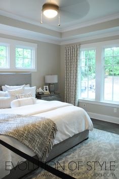 a large bed sitting in a bedroom next to two windows