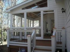 a porch with white railings and wooden steps leading up to the front door on a house