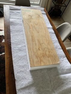 a table that has some kind of wood on top of it with white cloth around it