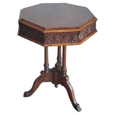 an octagonal wooden table with carved details on the top and legs, against a white background