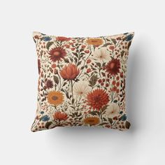 an orange and white pillow with red, yellow, and blue flowers on it's side