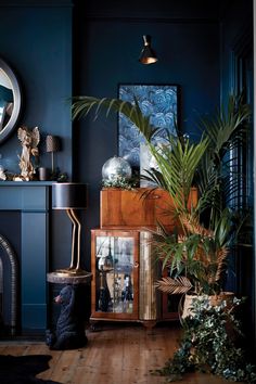 a living room with blue walls and wooden flooring, potted plants in the corner