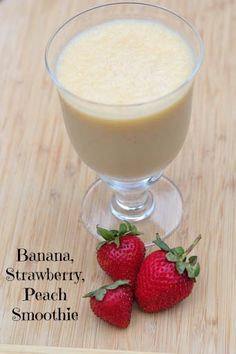 two strawberries sit on the table next to a glass of banana and strawberry smoothie