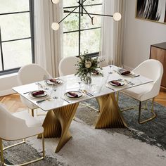 a dining room table with white chairs and gold accents