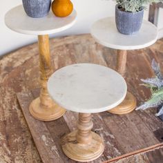 two small white tables sitting on top of a wooden table next to a potted plant