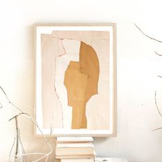 a white table topped with books next to a vase filled with flowers and a painting on the wall