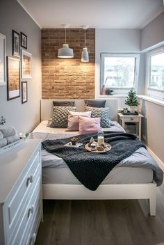 a bed sitting under a window next to a white table with food on top of it