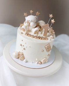 a white cake with gold stars and teddy bears on top, sitting on a plate