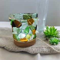 a glass vase sitting on top of a table next to a succulent plant