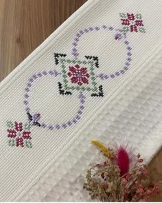 a cross - stitch pattern on a white cloth with flowers