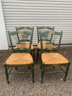 four green chairs sitting next to each other in front of a garage door on gravel