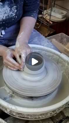 a woman is making a vase out of clay on a potter's wheel with her hands