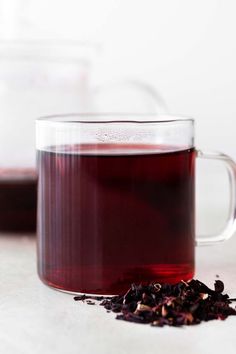 a glass mug filled with tea next to another cup