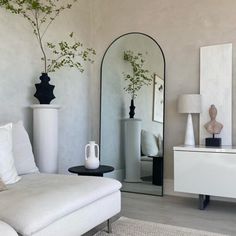 a living room with white furniture and mirrors