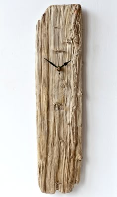 a clock made out of drift wood on the side of a wall with black hands