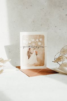 a card with an image of a bride and groom on it next to some flowers