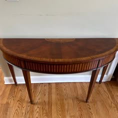 a wooden table sitting on top of a hard wood floor next to a white wall