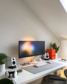 a desk with a monitor, keyboard and speakers on it