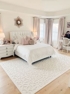 a white bed sitting in the middle of a bedroom next to a dresser and window