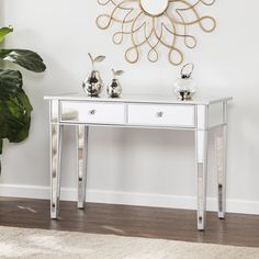 a white table with two drawers and a mirror on the wall next to a potted plant