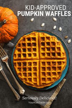 pumpkin waffles on a blue plate with fork and knife next to the waffle