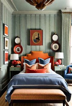 a bedroom with green walls, blue bedding and orange accents on the headboard