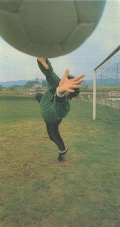 a person is reaching for a soccer ball in the air with their hands and feet