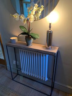 a vase with flowers on top of a wooden table next to a radiator