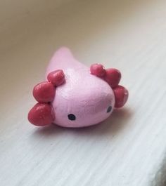 a close up of a pink toy animal on a white surface with black dots around it's eyes