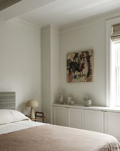 a bed sitting in a bedroom next to a window with white walls and wooden floors