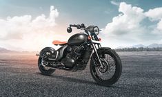 a black motorcycle is parked in the middle of an empty parking lot with mountains and clouds behind it