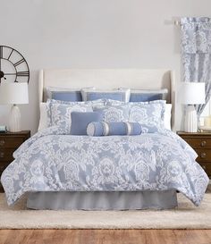 a bed with blue and white comforters in a bedroom next to two lamps on either side of the bed